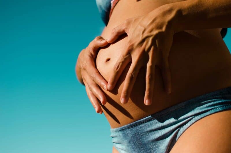 vernis semi permanent grossesse : femme enceinte faisant un coeur sur son ventre avec ses mains