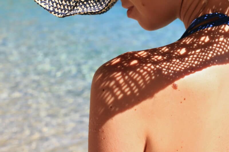 protéger sa peau du soleil : femme avec un chapeau qui fait de l'ombre sur sa peau