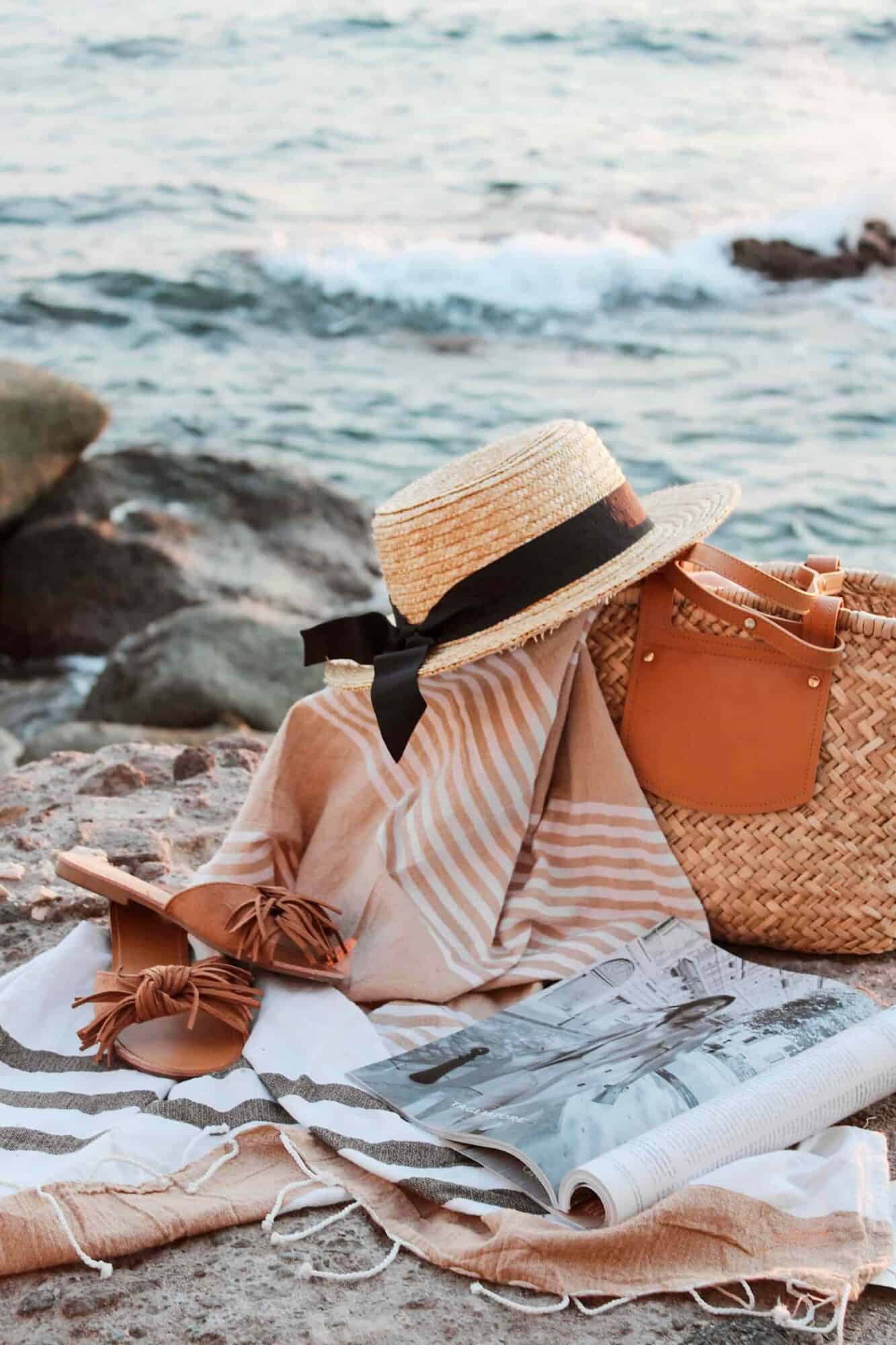 préparer sa peau au soleil : sac de plage, sandales et chapeau au bord de la mer