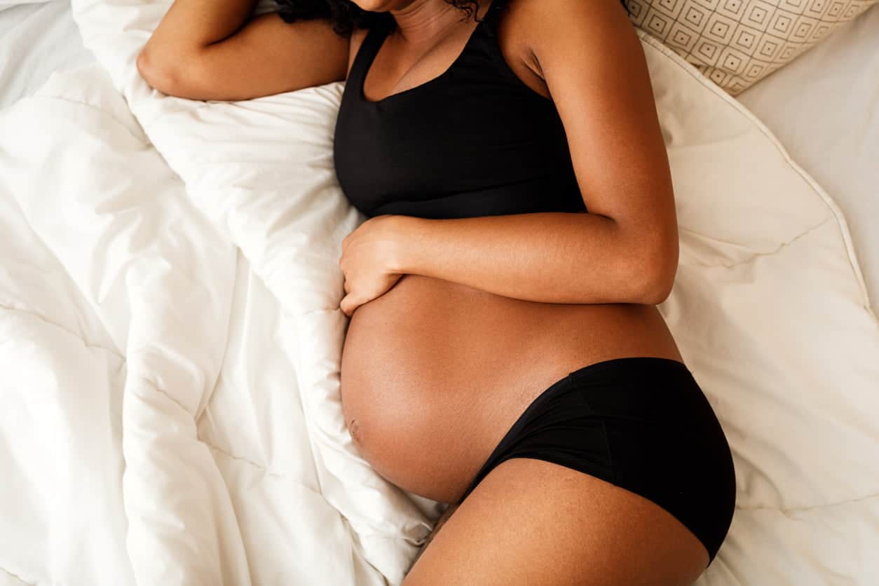 comment bien dormir enceinte : femme enceinte allongée sur un lit