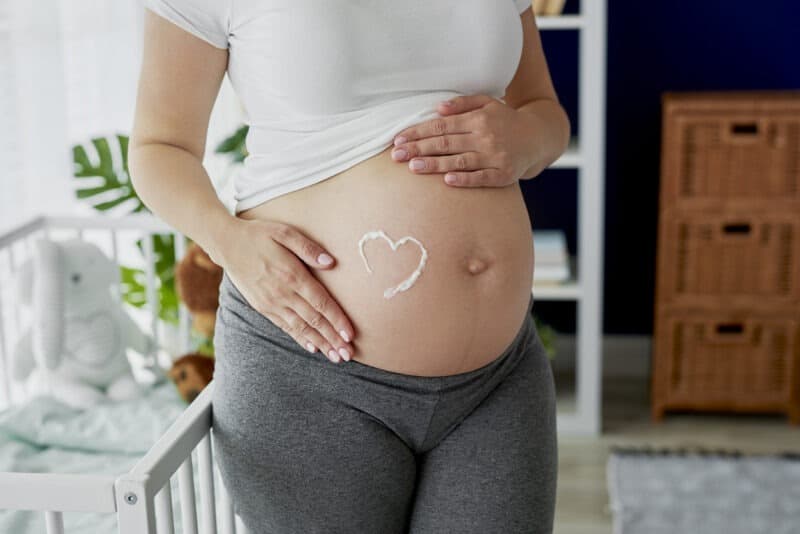 démangeaisons ventre grossesse : femme enceinte avec de la crème sur le ventre
