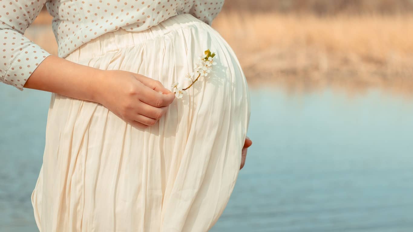 démangeaisons ventre grossesse : femme enceinte au bord d'un lac
