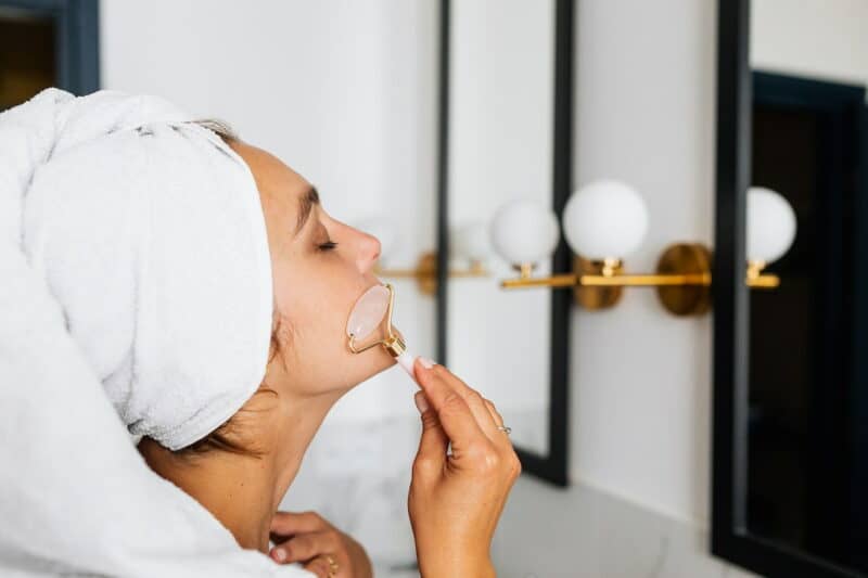 massage du visage bienfaits : une femme se masse le visage avec un gua sha