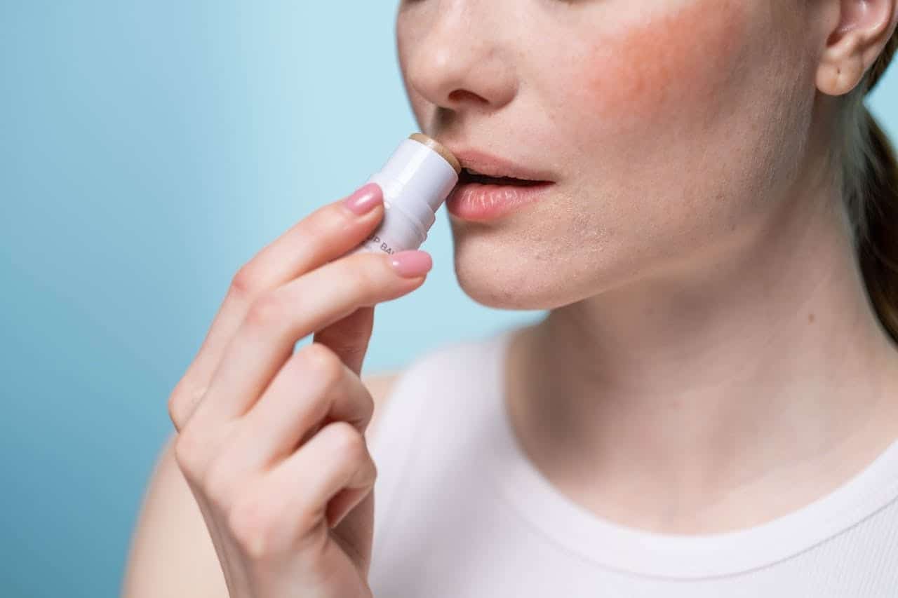 peau sensible en hiver : une femme se met du baume à lèvres