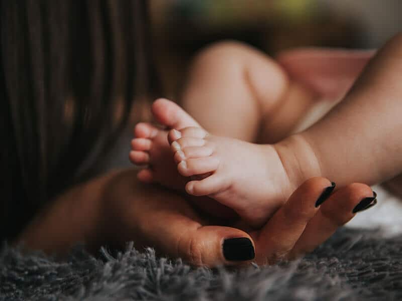 soins post partum : une mère tient le pied de son bébé